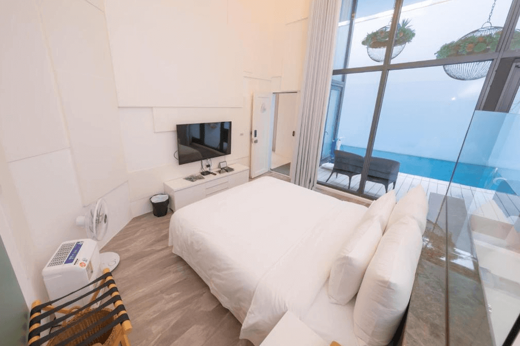 “頭城住宿”宜蘭PLAY Hotel飯店的一間帶有私人泳池的房間，房間內有一張大床，床前方有一台電視。落地窗直通室外的泳池區，讓房間充滿自然光線。室內設計現代簡約，以白色和淡木色為主。