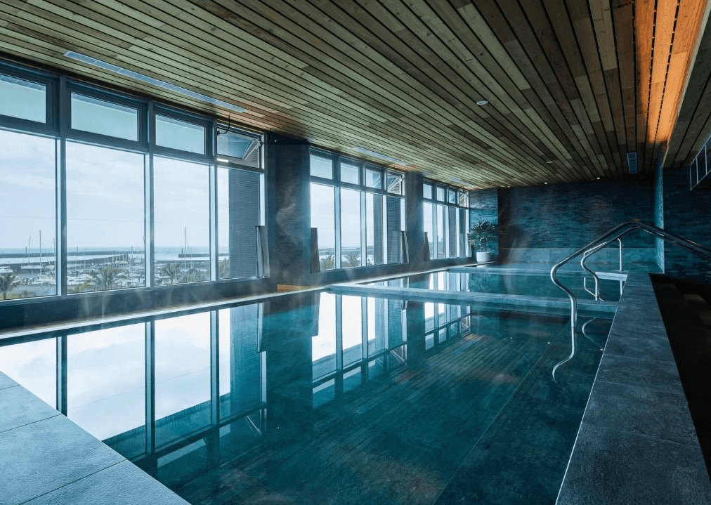 “頭城住宿”凱渡廣場酒店的室內溫泉池，溫泉池設計高雅，周圍牆面和天花板採用木質裝飾。透過大面積的窗戶，可以看到外面的碼頭景色，讓人在泡湯時也能欣賞到壯麗的海景。
