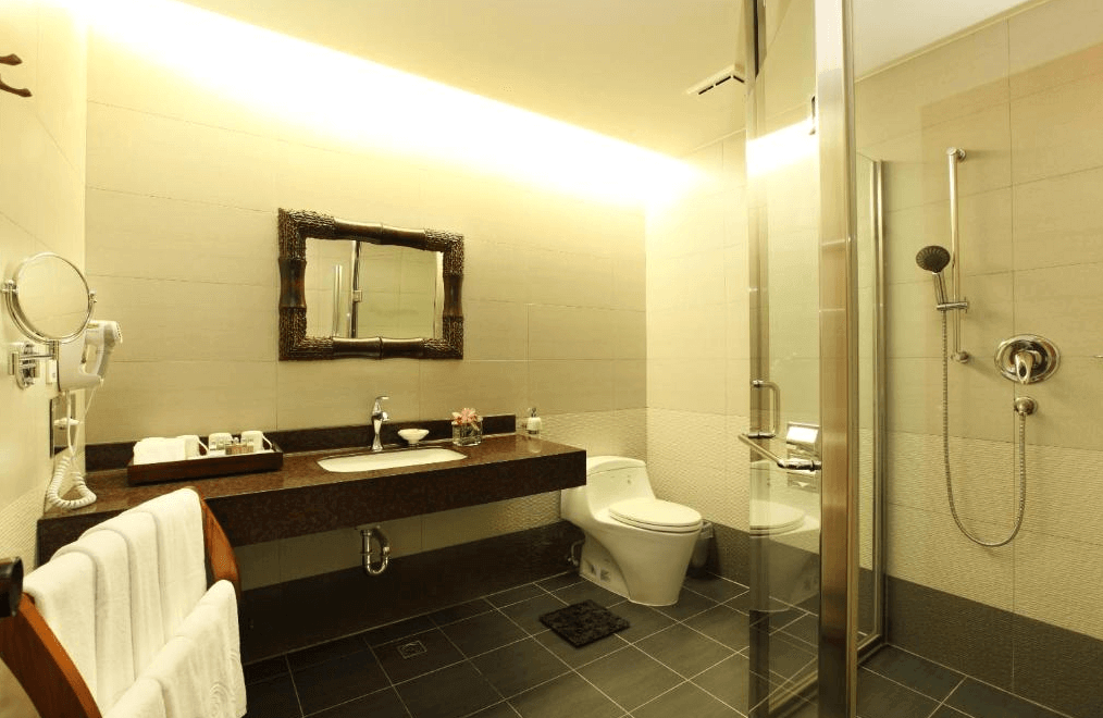 【墾丁寵物友善住宿】墾丁福華的浴室，設計現代簡約。浴室內有一面大鏡子和木框架的洗手台，配備乾濕分離的淋浴區，空間寬敞且乾淨。明亮的燈光讓整個空間顯得更加潔淨。