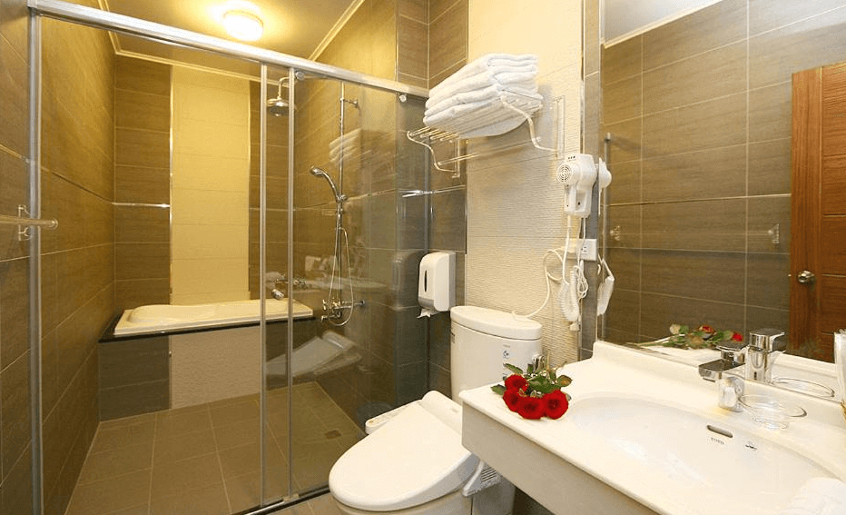 “頭城住宿”蘭博會館的浴室內部設計，配有玻璃淋浴間、浴缸和現代化的洗手台。浴室內的牆面和地板都使用了淺棕色的瓷磚，設計簡約而時尚，乾濕分離的配置讓空間更加實用。