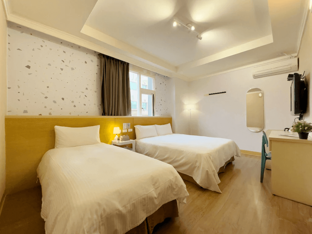 一起一起旅店花蓮中山館的雙床房配有兩張舒適的床鋪，牆上貼有細緻的圖案壁紙，增加視覺上的趣味性。房間裝飾簡約，帶有充足的燈光和自然光源，營造出明亮愉悅的住宿空間。