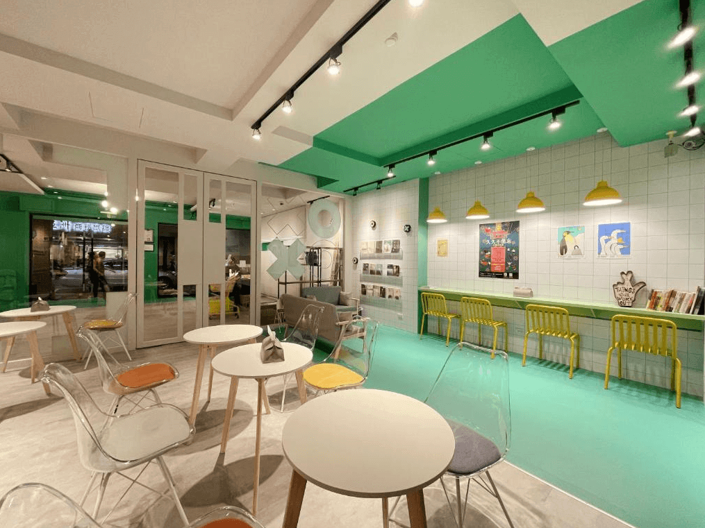 一起一起旅店花蓮中山館的公共空間以綠色和白色為主色調，搭配透明座椅和木質桌椅，整體風格年輕有活力。牆上擺放各式海報和藝術裝飾品，創造出輕鬆、充滿設計感的社交環境，適合旅客放鬆交流。