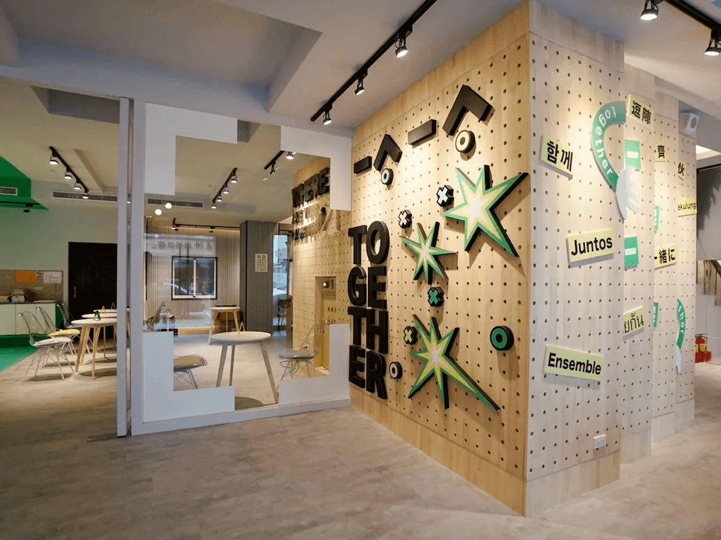 一起一起旅店花蓮中山館的區域以創意牆面為特色，牆上裝飾著 "TOGETHER" 字樣和各種語言的 "一起" 字句，並搭配立體的星星圖案，營造出多元且歡迎的氛圍。周邊擺放了簡約的桌椅，適合旅客聚集與互動。