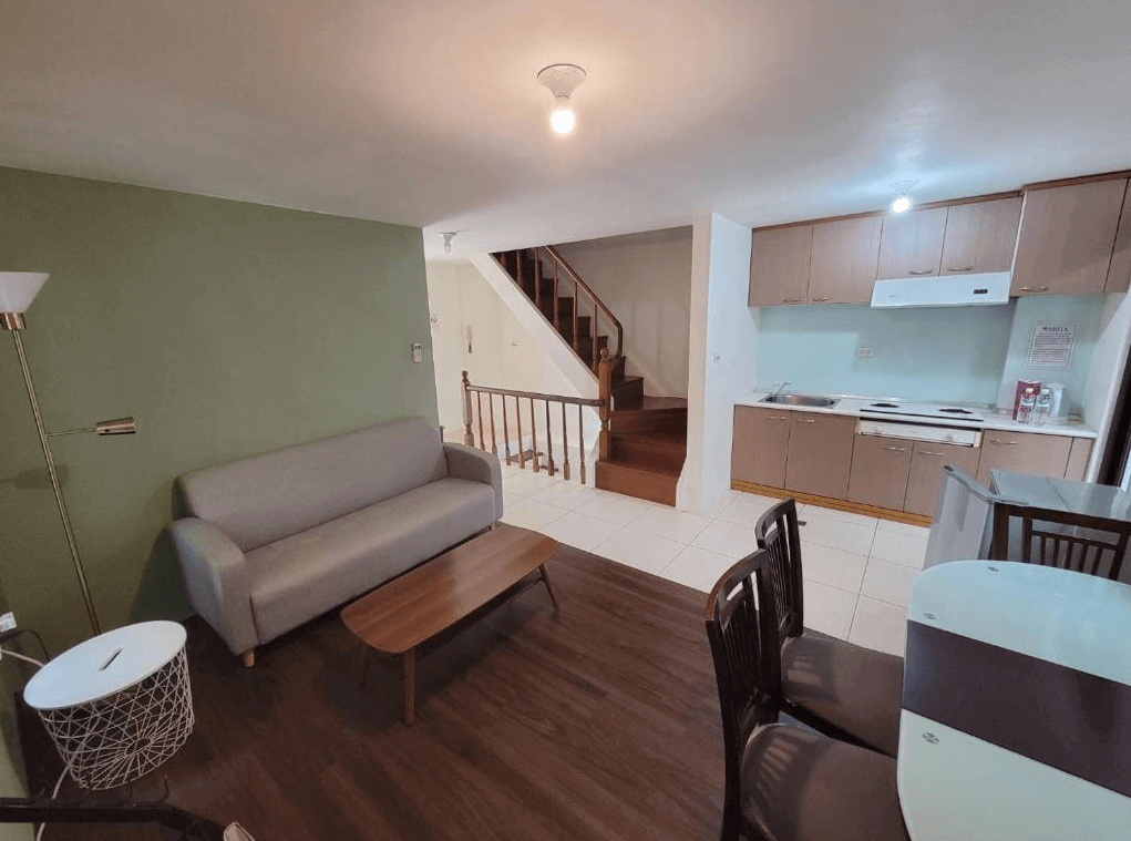 "三義住宿"三義幸福小築民宿具備廚房和客廳的小型套房，室內設有簡約的灰色沙發和木質茶几，廚房設備齊全，整體空間設計功能性強，適合家庭或長期住宿的旅客。