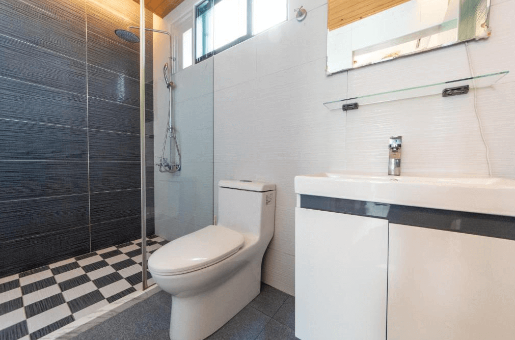 今古安民宿的現代化浴室，一間乾淨、現代化的浴室，配有一個深色瓷磚牆的步入式淋浴間。浴室內設有馬桶和帶儲物空間的洗手台，整潔且具現代感。