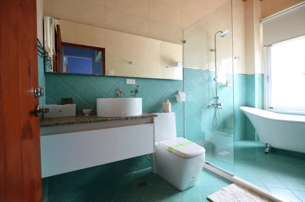 坲卡夏莊園民宿的浴室，設有玻璃淋浴間、白色座廁以及一個獨立浴缸，浴室牆壁和地板以清新淡雅的綠色瓷磚鋪設，窗外可以看到綠意盎然的風景，讓沐浴過程更加放鬆。