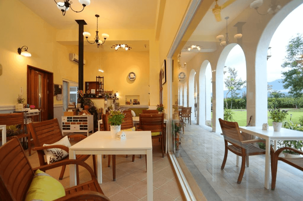 坲卡夏莊園民宿的室內用餐區，擁有高挑天花板與拱形落地窗，讓整個空間通透明亮。用餐區採用木質桌椅，外面還有陽台，提供了充滿自然光的舒適環境，適合享用早晨咖啡或下午茶。