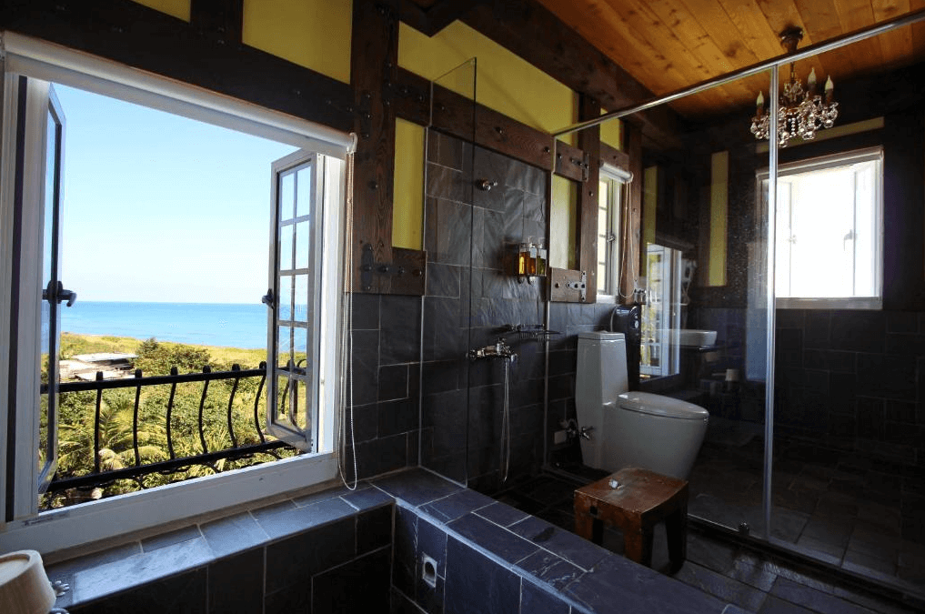 “花蓮寵物友善飯店”斯圖亞特海洋莊園的浴室，能直接眺望海景。浴室內牆以深色石材為主，搭配木質天花板，空間感十足，讓人能一邊享受寧靜的海景，一邊放鬆沐浴。