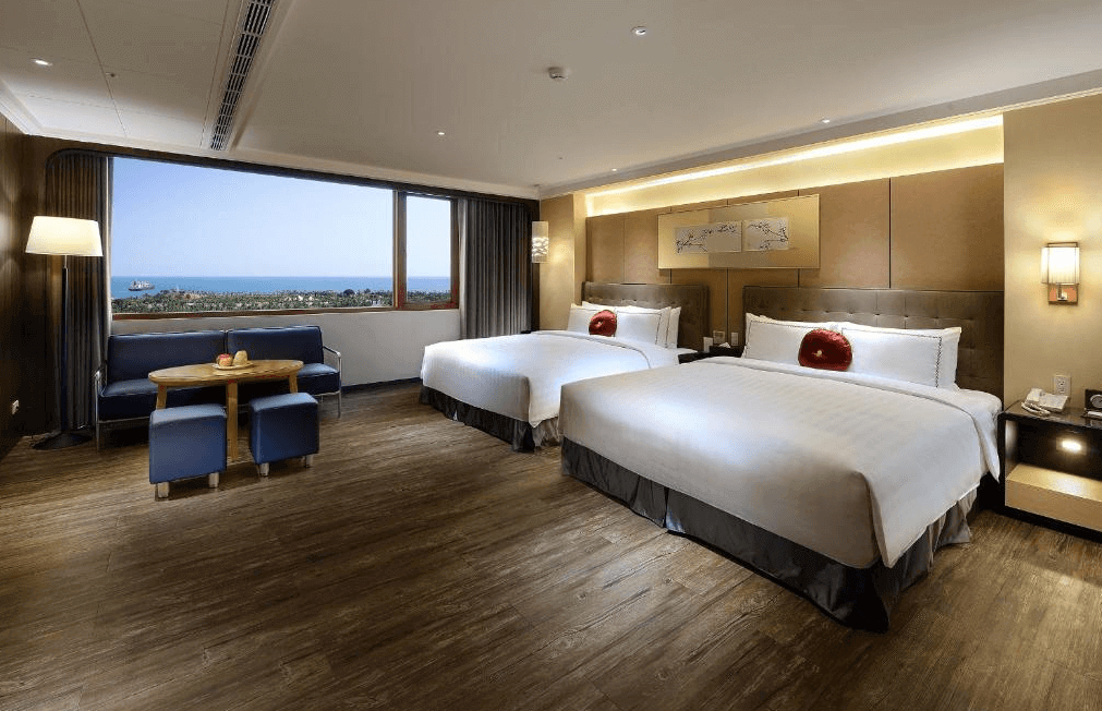 星空藍海飯店的雙床房帶有海景窗戶，提供開闊的景觀。房間設有兩張大床，搭配紅色靠墊，後方的牆面裝飾精美。房間內備有沙發區、木質餐桌和落地燈，營造出溫馨、舒適的住宿體驗。