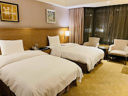 有人旅店的雙床房，兩張床鋪整潔而舒適。房間採用柔和的燈光搭配簡約的裝飾牆面，床旁有舒適的扶手椅及小桌子，整體氛圍溫馨舒適，非常適合放鬆。