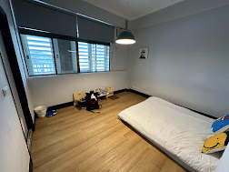 有人旅店的臥室，擺放了一張單人床，地板為木質設計，牆面淡雅且乾淨。房內布置簡單，僅有一些小型裝飾和玩偶，空間寬敞，適合尋求簡單住宿的旅客。