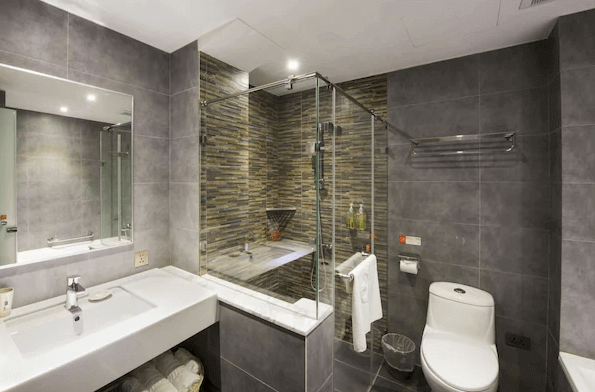 秝芯旅店駁二館的現代浴室 浴室內裝潢現代，牆面以灰色瓷磚為主，配有透明玻璃淋浴間和白色洗手台，整體設計簡約大方。乾濕分離的設計讓使用者感到舒適且方便，適合注重功能性與美觀的旅客。