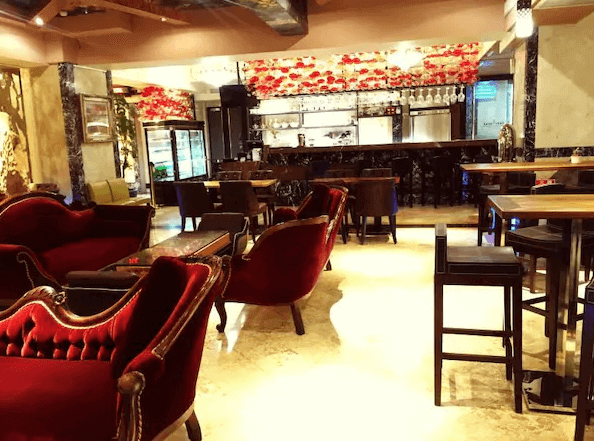 高雄漢王洲際飯店的休息區與咖啡廳 飯店的休息區內部裝潢豪華，紅色天鵝絨沙發搭配木質桌椅，營造出古典而溫馨的氛圍。天花板上方裝飾著華麗的燈具，背景牆上還有藝術裝飾，這裡適合旅客放鬆享用咖啡或休憩。