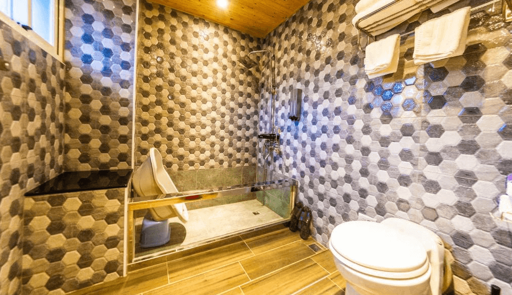 Have Fun玩樂親子旅宿的浴室，設計風格別緻，牆面覆蓋著六角形花磚，並有寬敞的淋浴空間，整體色調溫暖，呈現出高雅的質感。