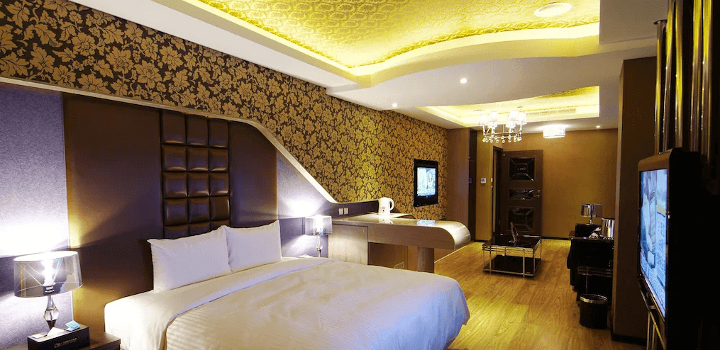 奇美國際時尚旅館的古典與現代風格的客房，天花板採用金色花紋設計，房內設有雙人床、按摩浴缸及電視，燈光柔和，展現出高級的住宿體驗。
