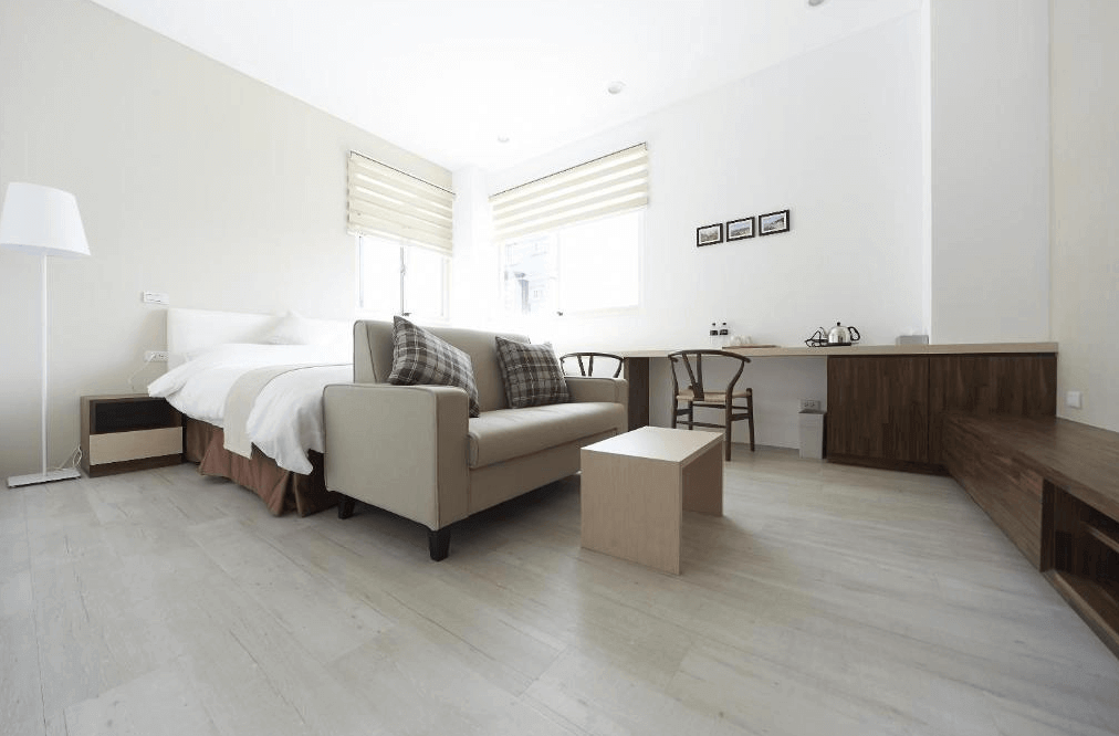 好漾民宿youngstay的寬敞雙人房，內有一張雙人床和米色沙發，擺放著舒適的枕頭。房間設計簡潔明亮，採光良好，配有長型書桌和木質收納櫃，營造出舒適的住宿環境。