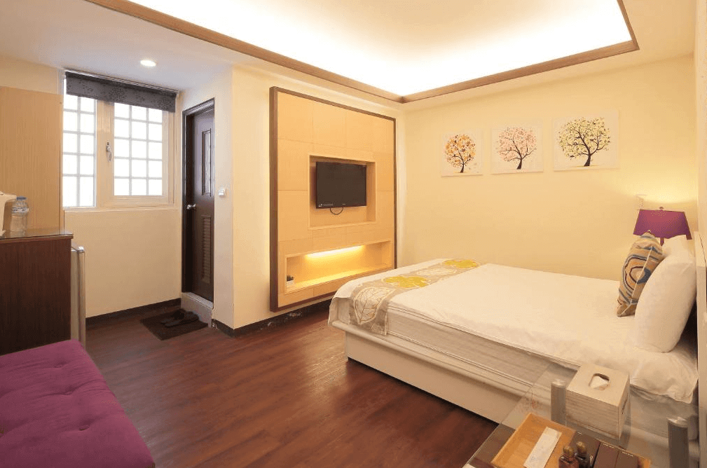 幸福YES民宿三館的單人房，配有一張大床，牆上裝飾著三幅樹木圖案的畫作。房間內有木質電視牆，整體色調柔和，呈現舒適的氛圍。