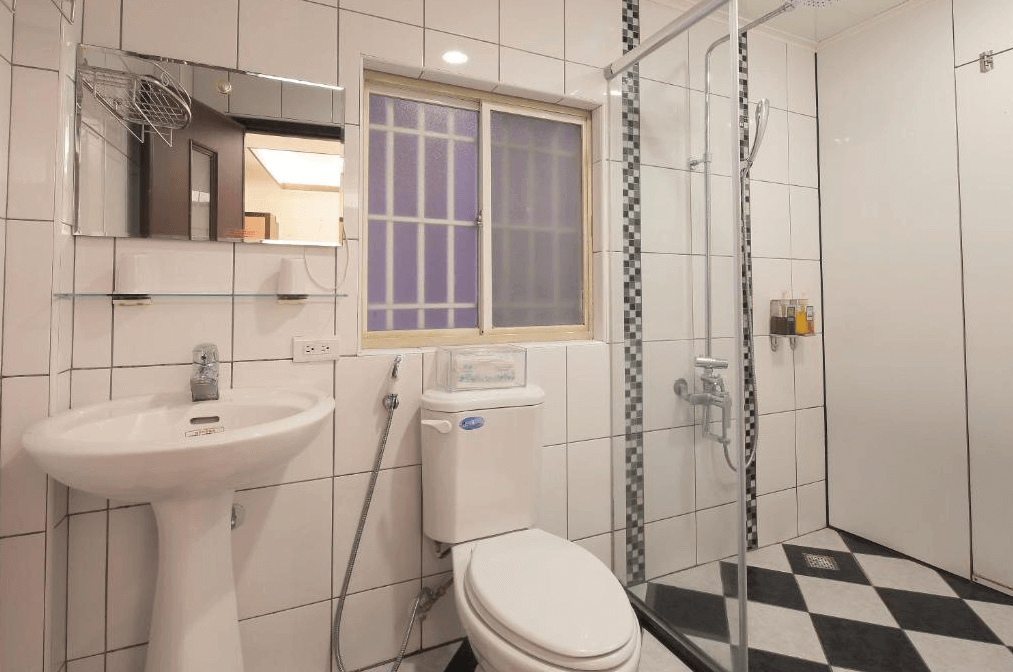 幸福YES民宿三館的浴室，設有獨立的淋浴間和馬桶，牆面以白色瓷磚裝飾，搭配黑白格子地磚，空間簡潔且明亮。