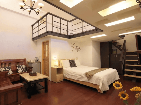 幸福YES民宿二館一間帶有夾層設計的房間，下層有一張雙人床與傳統木製沙發區，房間裝潢風格溫馨且具有特色，木質地板與吊燈營造出復古氛圍。