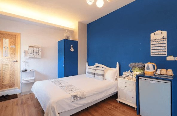 幸福YES民宿二館一間以藍色為主色調的房間，內有一張雙人床，牆壁和家具都帶有海洋風格的裝飾，散發出輕鬆愉悅的氛圍，適合喜愛海洋風情的旅客。