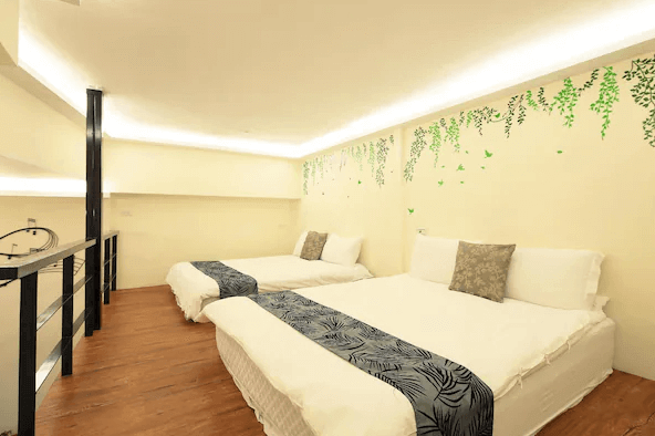 幸福YES民宿二館的夾層區域，設有兩張雙人床，牆面裝飾有綠葉圖案，營造出自然放鬆的氛圍。此區域適合多人一起入住，增加住宿的趣味性。