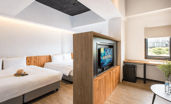 旅人驛站鐵花紋創館的房間設有兩張大床,適合家庭或朋友一同入住。中央的木質隔屏不僅增添自然質感,也巧妙地將空間分隔為休息區和娛樂區。旁邊的窗戶提供了充足的自然光,使房間更顯明亮、通風。