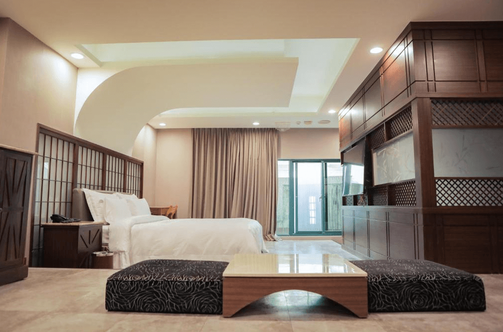 【新營汽車旅館】歐悅連鎖精品汽車旅館-新營館典雅和風設計的寬敞房間，床鋪旁邊設有和室風格的小茶几，落地窗提供充足的自然光。