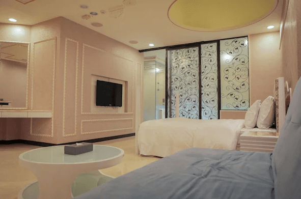 【新營汽車旅館】歐悅連鎖精品汽車旅館-新營館柔和浪漫風格的房間，配有精緻的牆面裝飾和大面積的鏡子，帶有寬敞的床和舒適的沙發區。