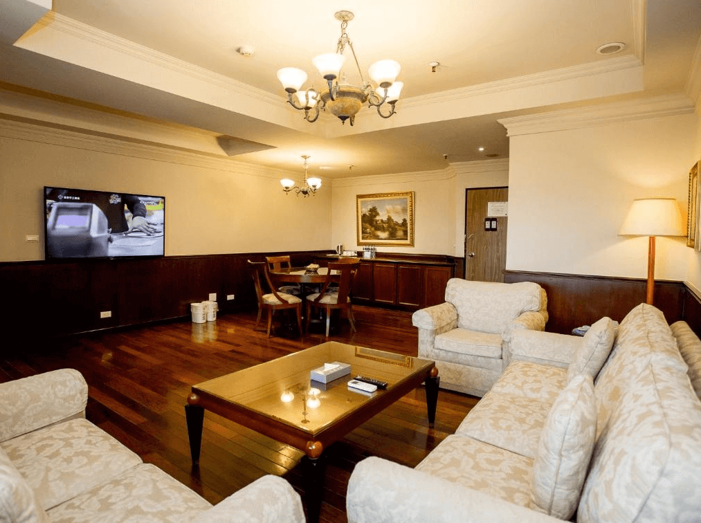 玖屋文旅的寬敞客廳，採用木質地板和古典家具擺設，有沙發和木製餐桌。室內裝潢帶有典雅氣息，配有吊燈和裝飾畫，營造出溫馨的居家氛圍。