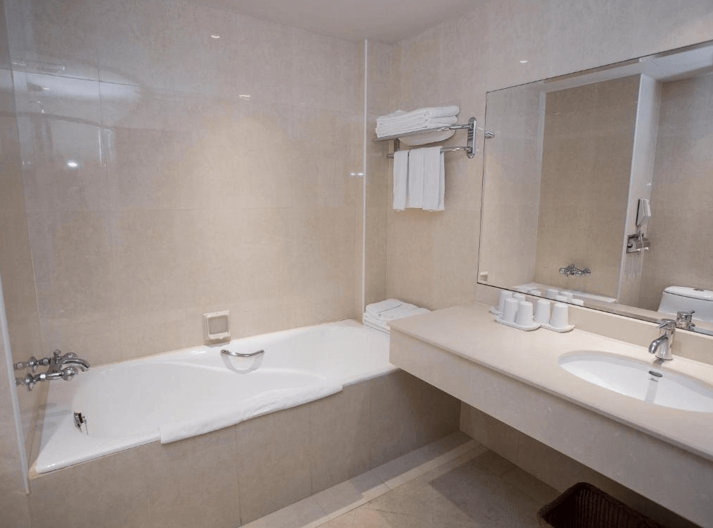 玖屋文旅的浴室，配有浴缸和大理石檯面。牆壁和地板皆為淺色瓷磚，整體風格簡潔明亮，設施擺放整齊，給人潔淨的感覺。