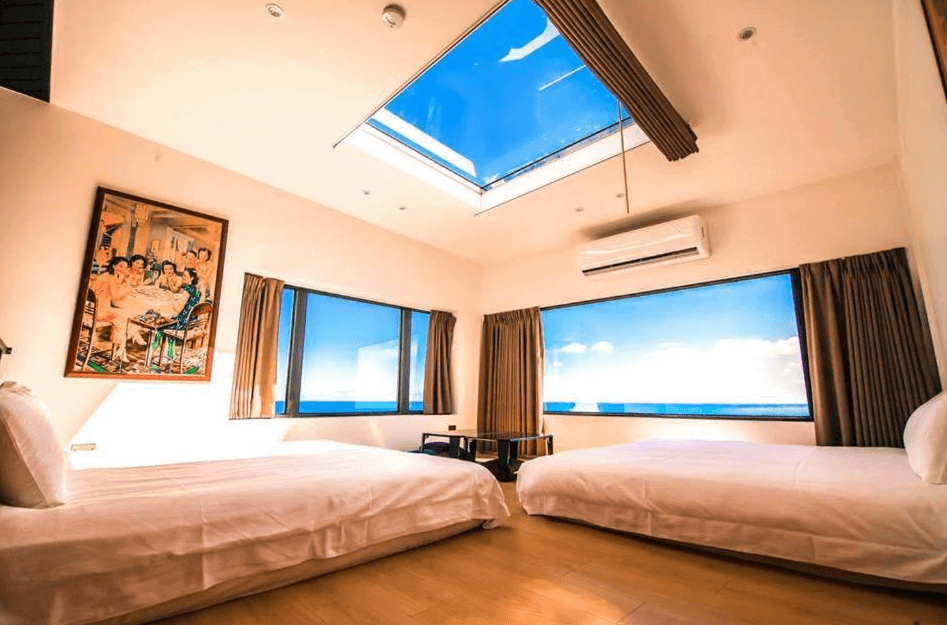 【小琉球住宿】琉球茶室復古館擁有天窗設計的海景房，房內配有兩張大床，窗戶外是蔚藍的大海景色，牆上掛著懷舊風格的畫作，整體氛圍溫暖且開放。