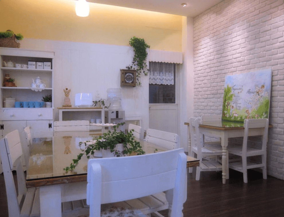 甜蜜家101的餐廳裝潢以白色為主，搭配鄉村風的木質餐桌椅和牆上綠意點綴，牆面上還有可愛的插畫板，讓整體空間顯得溫馨而充滿田園氣息。
