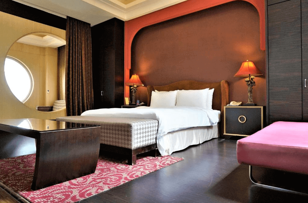 【新營汽車旅館】禾楓水舍汽車旅館高雅浪漫的房間設計，採用深色調牆面搭配圓形窗戶和紅色床頭燈，營造出舒適且溫馨的氛圍。