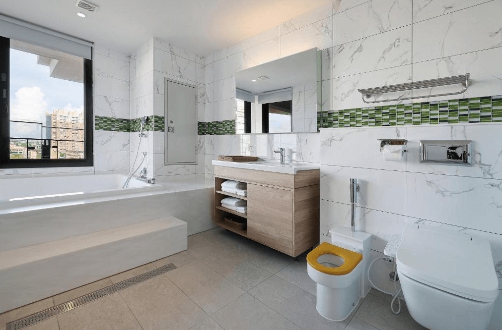 雀客童媽吉親子旅館的浴室，配有寬敞的浴缸和簡約的木質盥洗檯。牆面使用大理石瓷磚搭配綠色馬賽克設計，並有大面窗戶可透進自然光。