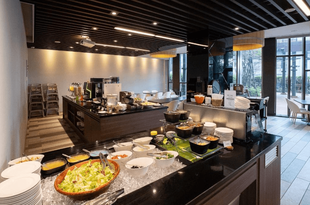 雀客童媽吉親子旅館的自助餐餐廳，設有各式沙拉、湯品和主菜選擇。整體裝潢以木質元素為主，採用溫暖的燈光，營造出輕鬆愉快的用餐氛圍。