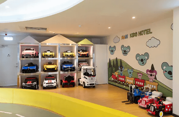 雀客童媽吉親子旅館的兒童遊樂設施區域，展示各種兒童迷你車，牆上裝飾有可愛的卡通圖案。空間色彩鮮豔，設計以親子友善為主，提供小朋友娛樂的場所。