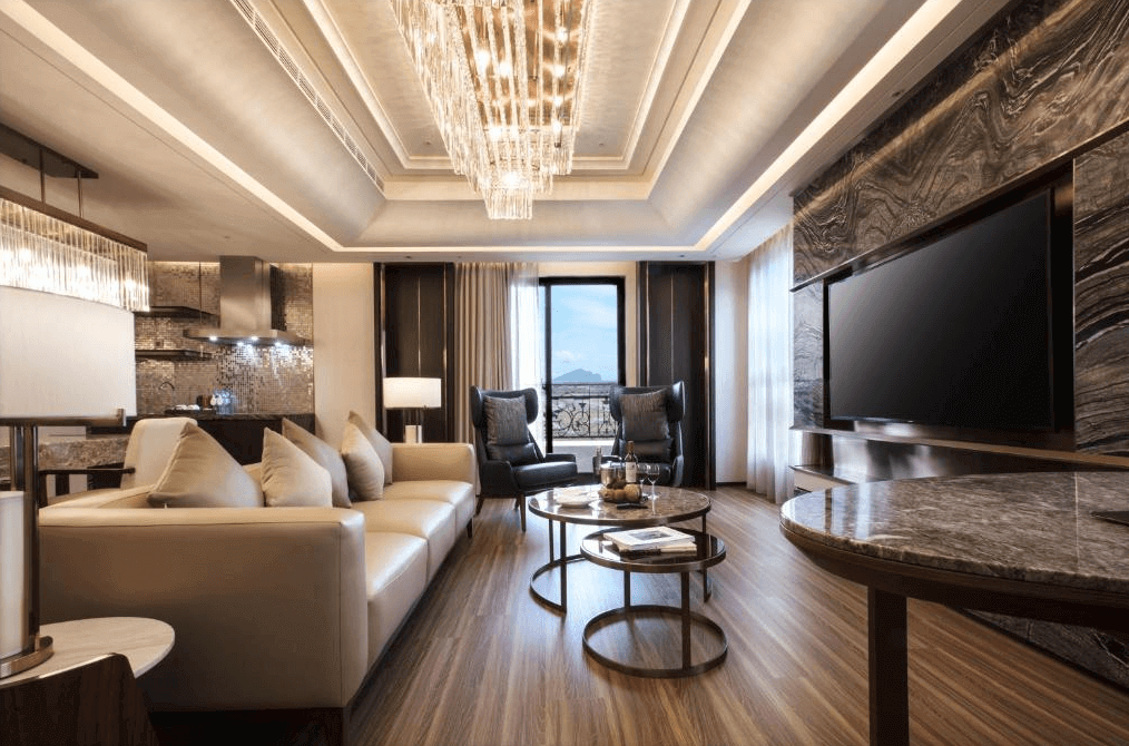 【礁溪住宿】中天溫泉渡假飯店的豪華客廳空間，擁有大理石電視牆、吊燈與寬敞沙發，木質地板與窗外的自然景色相得益彰，整體呈現高端大氣的氛圍。