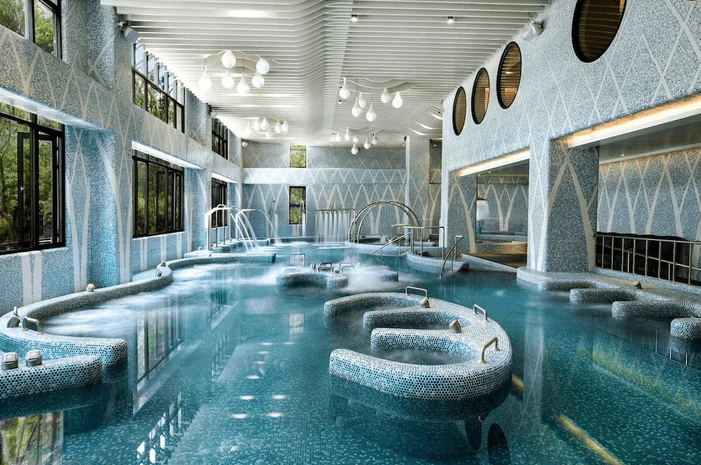 【礁溪住宿】中天溫泉渡假飯店的飯店室內溫泉設施，設有多功能泡湯區與水療設備，整體以藍白馬賽克瓷磚裝飾，空間明亮寬敞，營造放鬆的氛圍。