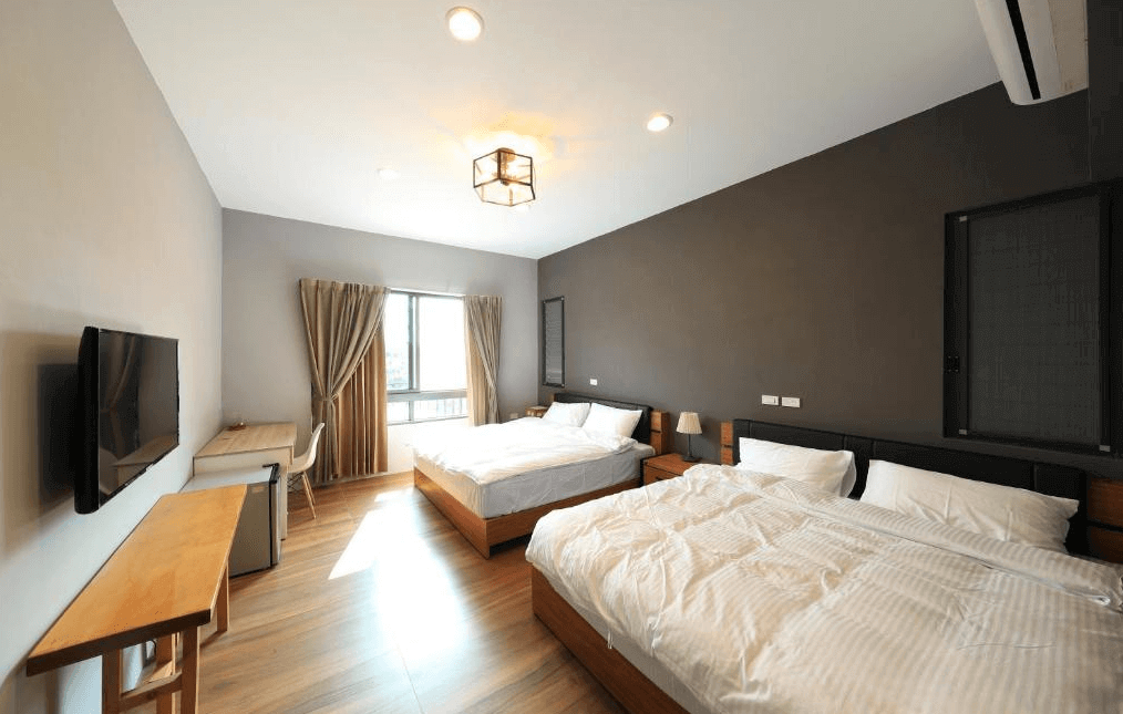 【水里住宿】五山三水莊園民宿的雙大床家庭房，牆面採用深灰色與白色對比，展現簡約時尚感。房間內設有書桌與椅子，窗外風景怡人，整體空間感寬敞明亮，非常適合家庭旅客入住。