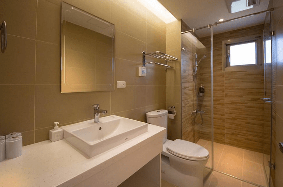 【通霄住宿】南窩綠丘現的浴室，牆面及地板鋪設淺色系磁磚，設有獨立乾濕分離淋浴間。白色洗手台與馬桶乾淨整潔，搭配鏡面設計及柔和燈光，營造高級而放鬆的洗浴空間。