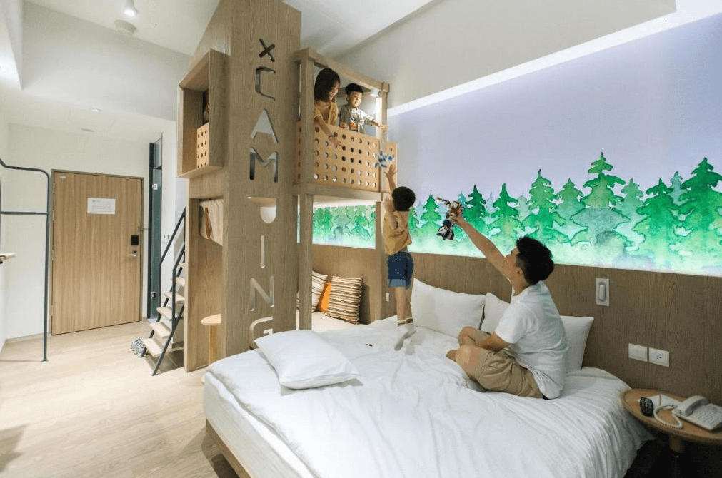 【礁溪住宿】品文旅礁溪親子氛圍的房間，設有上下舖床架，木製結構刻有「CAMPING」字樣，房內牆面繪有森林圖案，家人互動其樂融融，展現溫馨的入住體驗。
