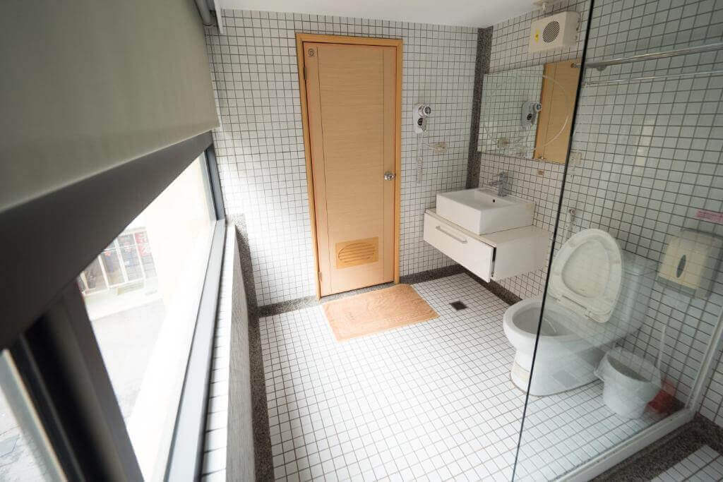 【北港住宿】好住民宿的浴室設計以簡約白色瓷磚為主，搭配大窗戶提供自然採光，配有乾濕分離設施與簡潔的衛浴設備，整體清新整潔且實用。