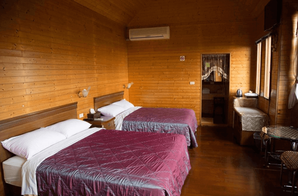 【通霄住宿】如意園民宿以全木質打造的雙床房，溫暖自然的色調。房間內設有兩張雙人床、壁燈及基本設施，窗邊有簡單茶座，提供溫馨且舒適的住宿體驗。