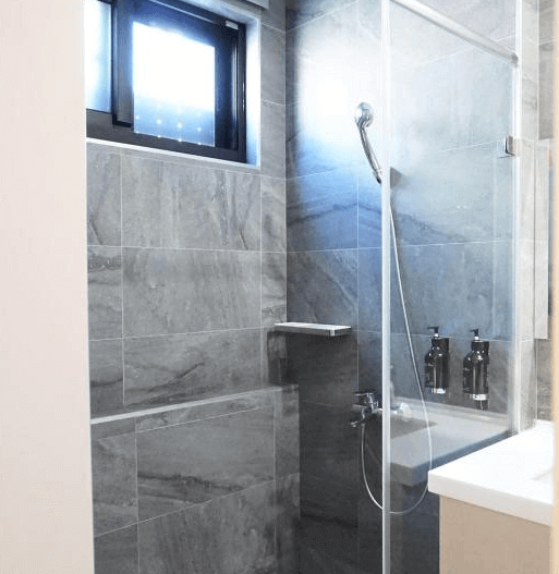 【水里住宿】恩典花園咖啡民宿的浴室設計採用深色大理石磁磚，搭配玻璃乾濕分離淋浴空間，整潔現代，細節處理考究，讓人感受舒適的使用體驗。