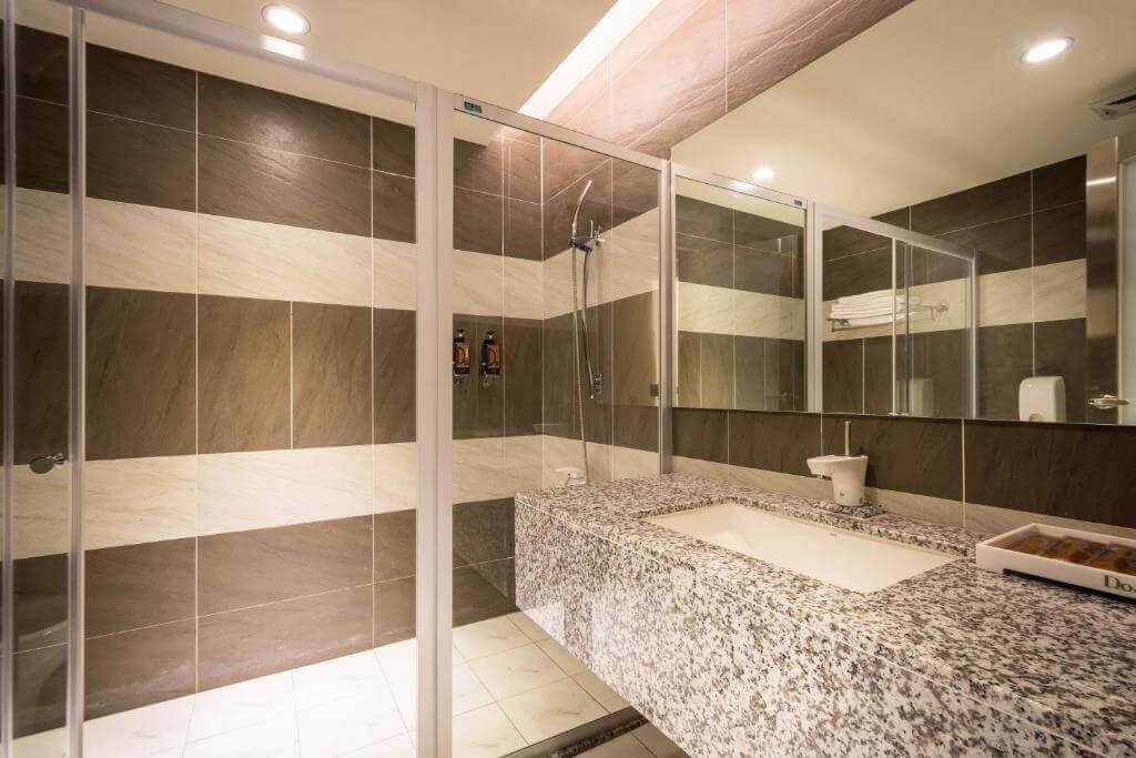 【北港住宿】愛妮雅汽車旅館的浴室以大理石紋洗手台搭配深淺相間的磁磚設計，乾濕分離淋浴間提供舒適的使用體驗，整體感覺整潔而時尚。