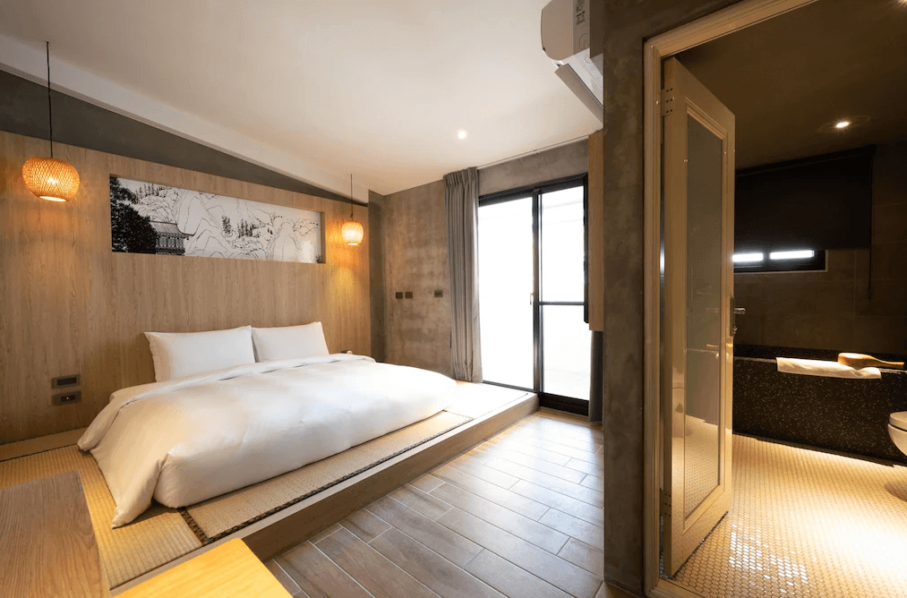 【礁溪住宿】東旅湯宿溫泉飯店-風華漾的日式風格溫泉客房，室內採用木質地板和榻榻米設計，搭配舒適的雙人床，燈光柔和，牆面裝飾有東方山水畫，房間連接一間設計簡約的浴室，配備現代化設施。