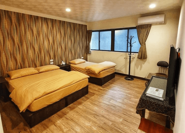 【水里住宿】樂水軒民宿雙床與單床併存的客房，牆面搭配抽象紋理壁紙，營造出獨特的視覺效果。房間設有木質地板，整體風格溫馨，適合小家庭或朋友共享入住。