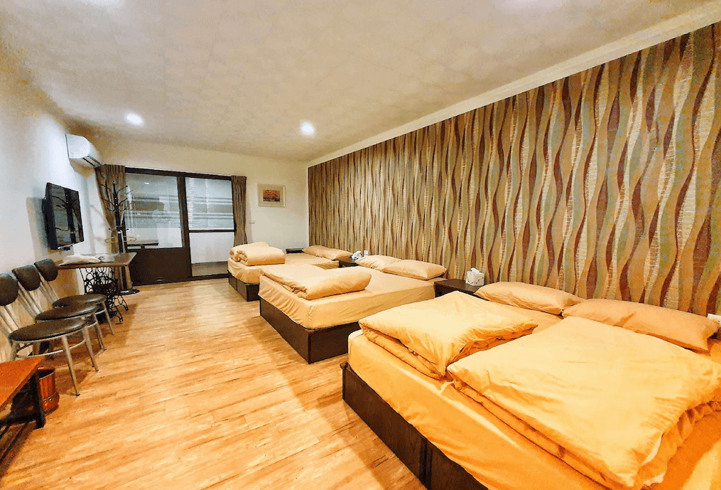 【水里住宿】樂水軒民宿的多人房間設有多張床位，寬敞的空間能容納多人同時入住，適合團體或家庭旅行使用。房間內的設計風格簡約實用，並以暖色調營造舒適氛圍。