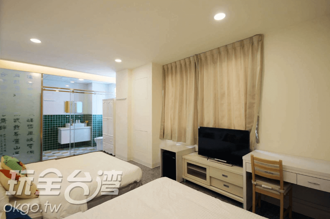 【北港住宿】水道頭咖啡民宿的房間內設有兩張床，搭配簡約現代的家具設計，旁邊為透明玻璃衛浴間，牆面上刻有書法詩句，展現了文化與現代感兼具的特色。