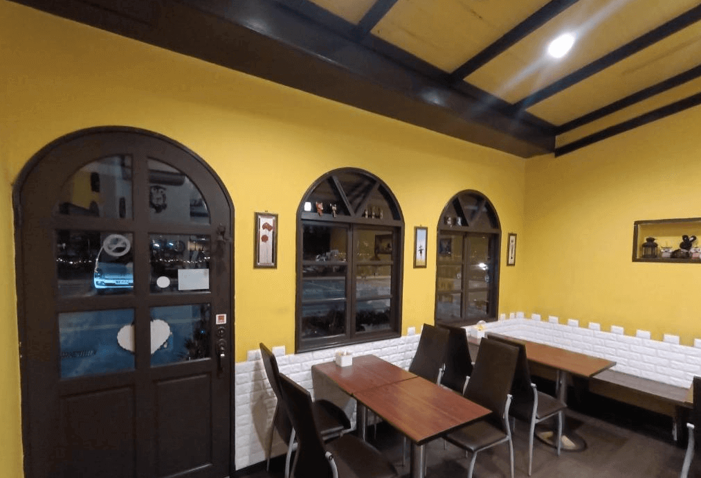 【水里住宿】水里河堤咖啡民宿餐廳區域，牆面以溫暖的黃色搭配拱形窗戶，帶有濃厚的鄉村風情。木質桌椅與白色磚牆相得益彰，提供一個舒適的用餐空間。